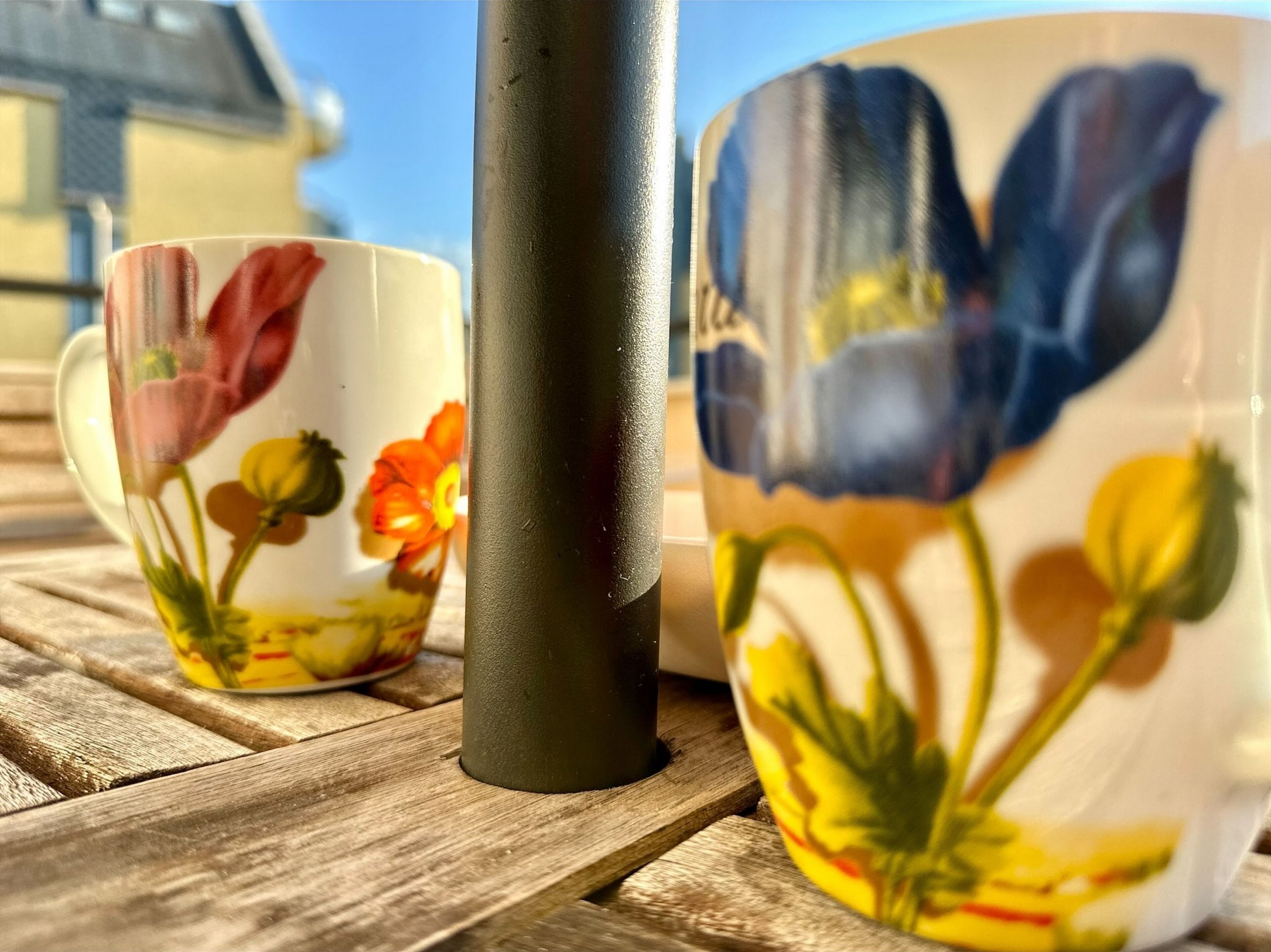 Deux tasses en céramique ornées de motifs floraux, posées sur une table en bois.