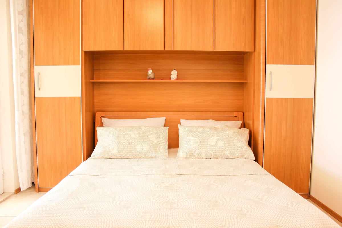 A bedroom with a wooden headboard, two bedside tables, and a bed with patterned bedding.