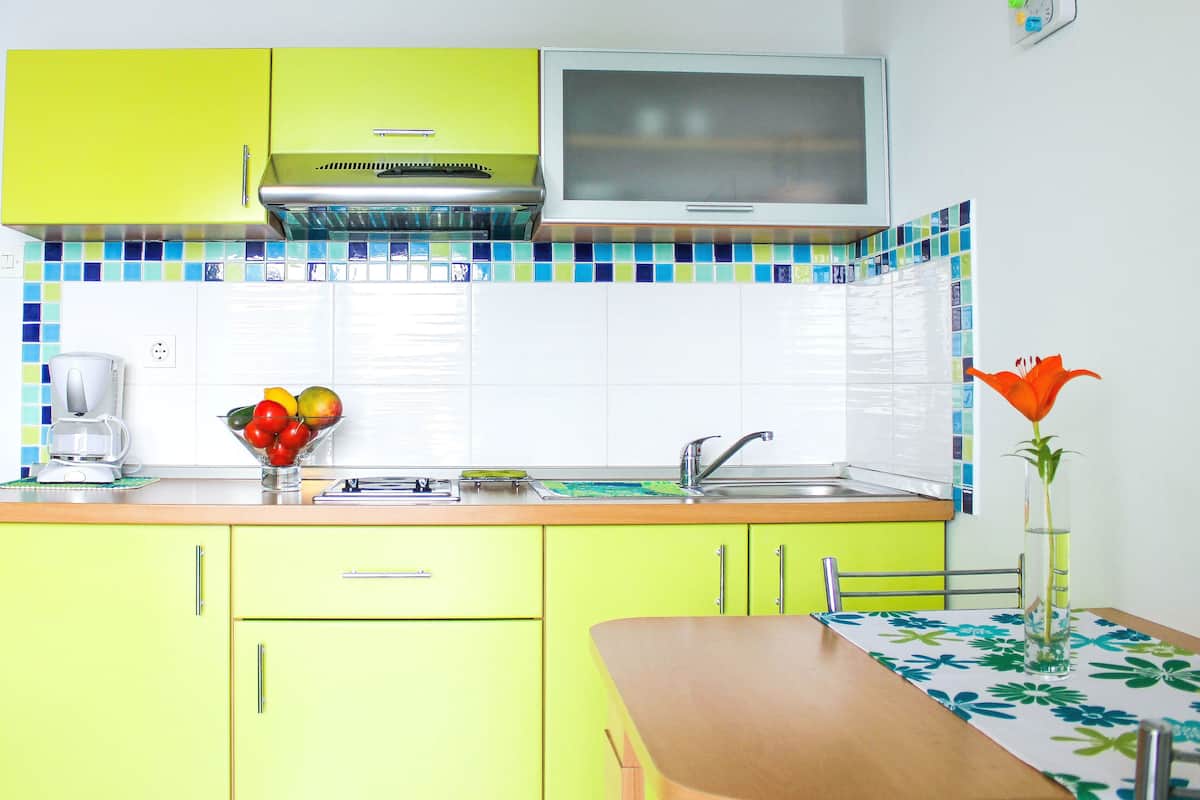 A kitchen with a microwave, sink, and a bowl of fruit on the counter.