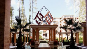 A courtyard with a central fountain, palm trees, and a geometric sculpture. - Menada Apartments in Tarsis Nova Complex (Sunny Beach)