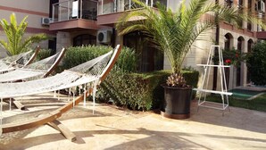 A hotel courtyard with multiple hammocks, a palm tree, and a ladder. - Menada Apartments in Tarsis Nova Complex (Sunny Beach)