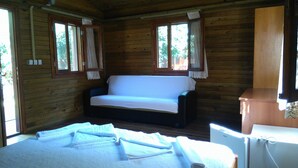A cozy cabin room with a wooden interior, a white sofa, and a small table with a lamp.