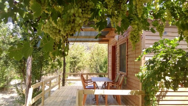 A wooden cabin with a covered porch, a table, and chairs.