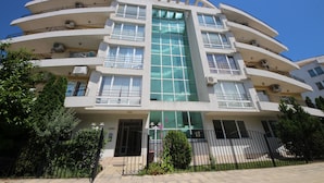 A multi-story building with balconies, large windows, and a central glass facade. - Menada Apartments in Azzuro Hotel (Sunny Beach)