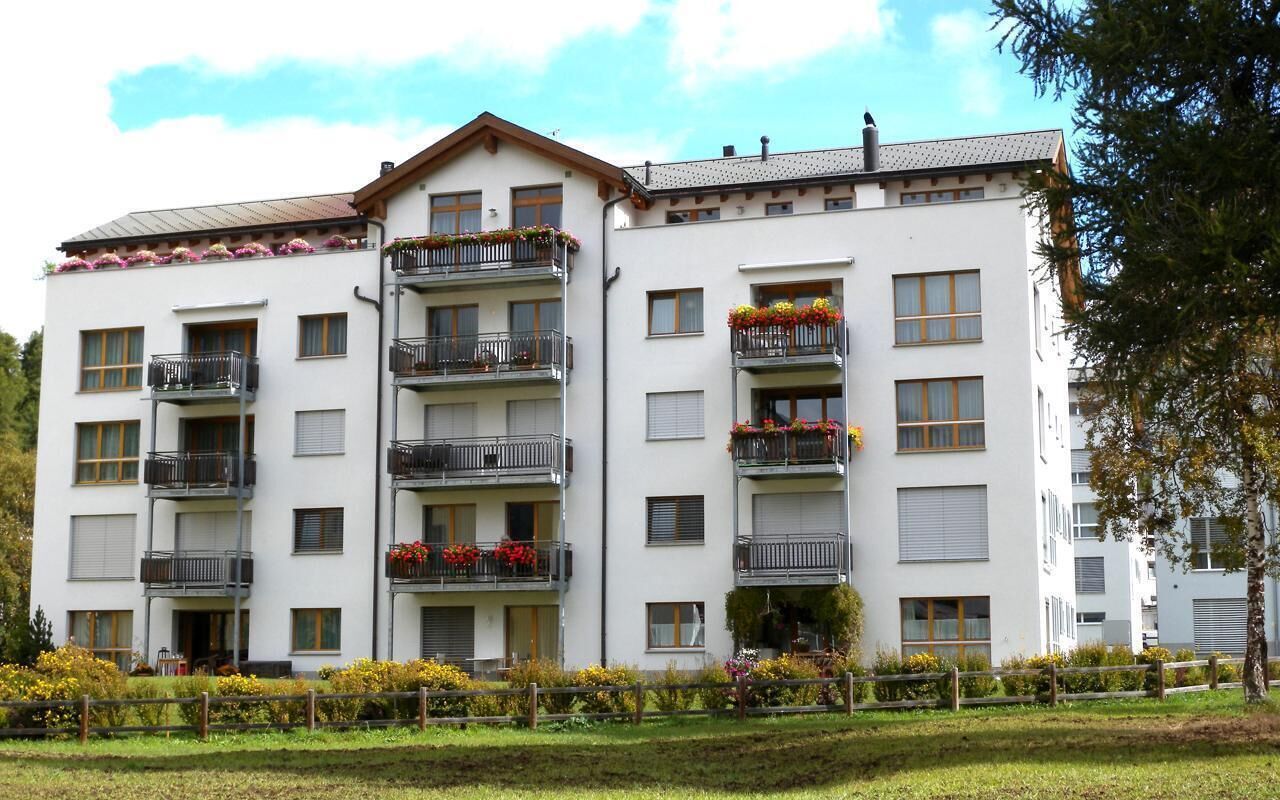 A multi-story residential building with balconies, windows, and a well-maintained garden.