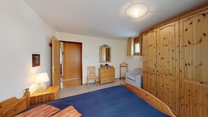 Un dormitorio con cama, armario de madera, cómoda, silla y espejo.