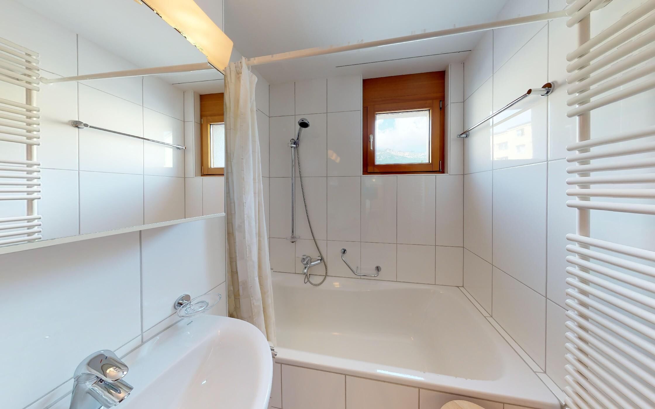 Ein modernes Badezimmer mit einer Badewanne, einer Dusche und einem Fenster.