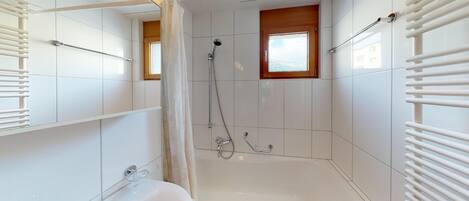 Ein modernes Badezimmer mit einer Badewanne, einer Dusche und einem Fenster.