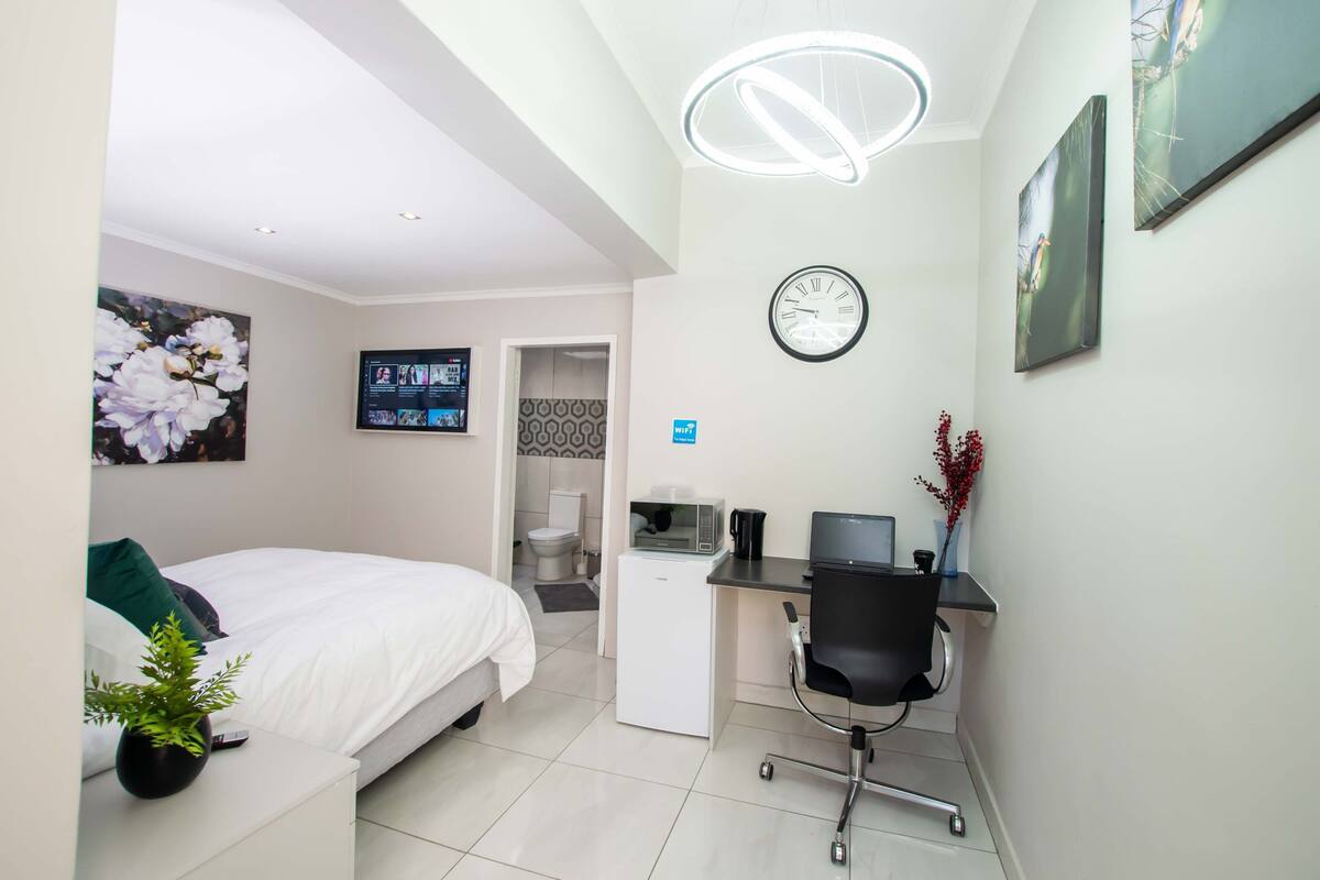 A modern hotel room with a bed, desk, and seating area.