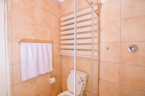 Un baño con ducha, inodoro y una toalla colgada en la pared.