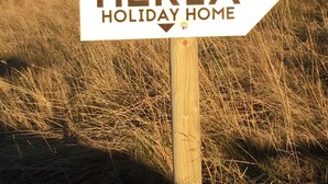 A wooden signpost with a white arrow pointing to the right, labeled "HEKLA HOLIDAY HOME". - Hekla Holiday Home (Storinupur)