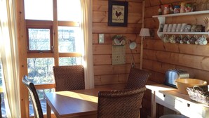A wooden interior with a dining table, wicker chairs, a calendar, and shelves with kitchenware. - Hekla Holiday Home (Storinupur)