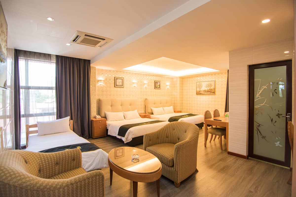 A hotel room with two beds, a sofa, a dining table, and a small table.