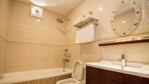 Un baño con bañera, inodoro, tocador y espejo.