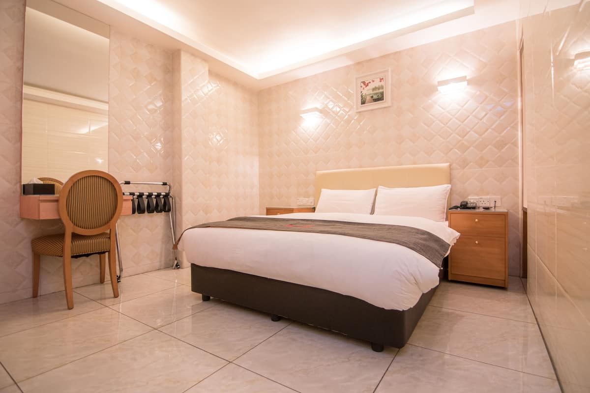 A neatly arranged bedroom with a bed, bedside table, chair, and a mirror.