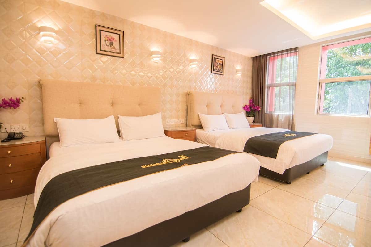A hotel room with two beds, a large window, and a decorative wall.