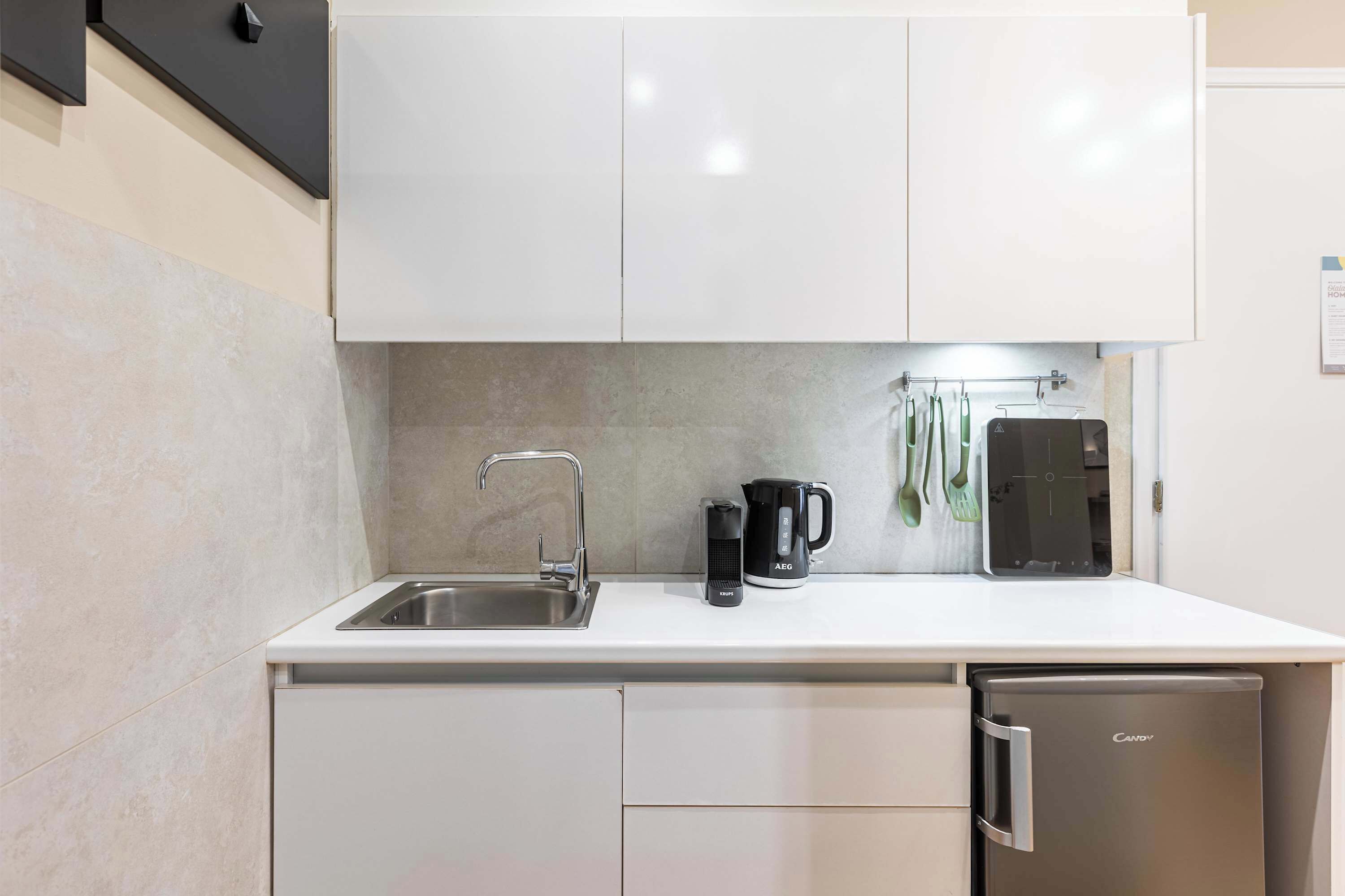A compact kitchen with a sink, a coffee maker, and a compact refrigerator.