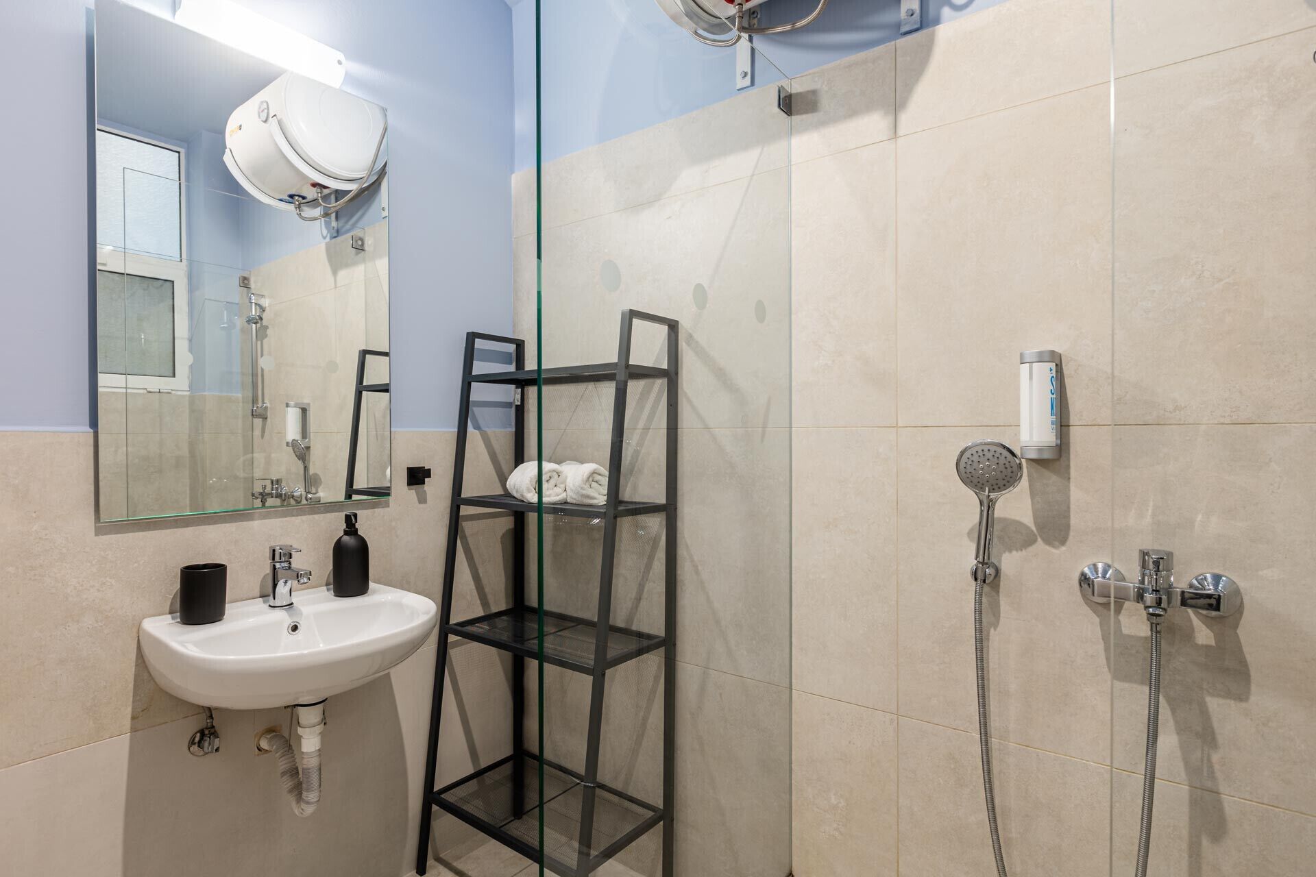 Een moderne badkamer met een wastafel, spiegel, handdoekrek en douche.