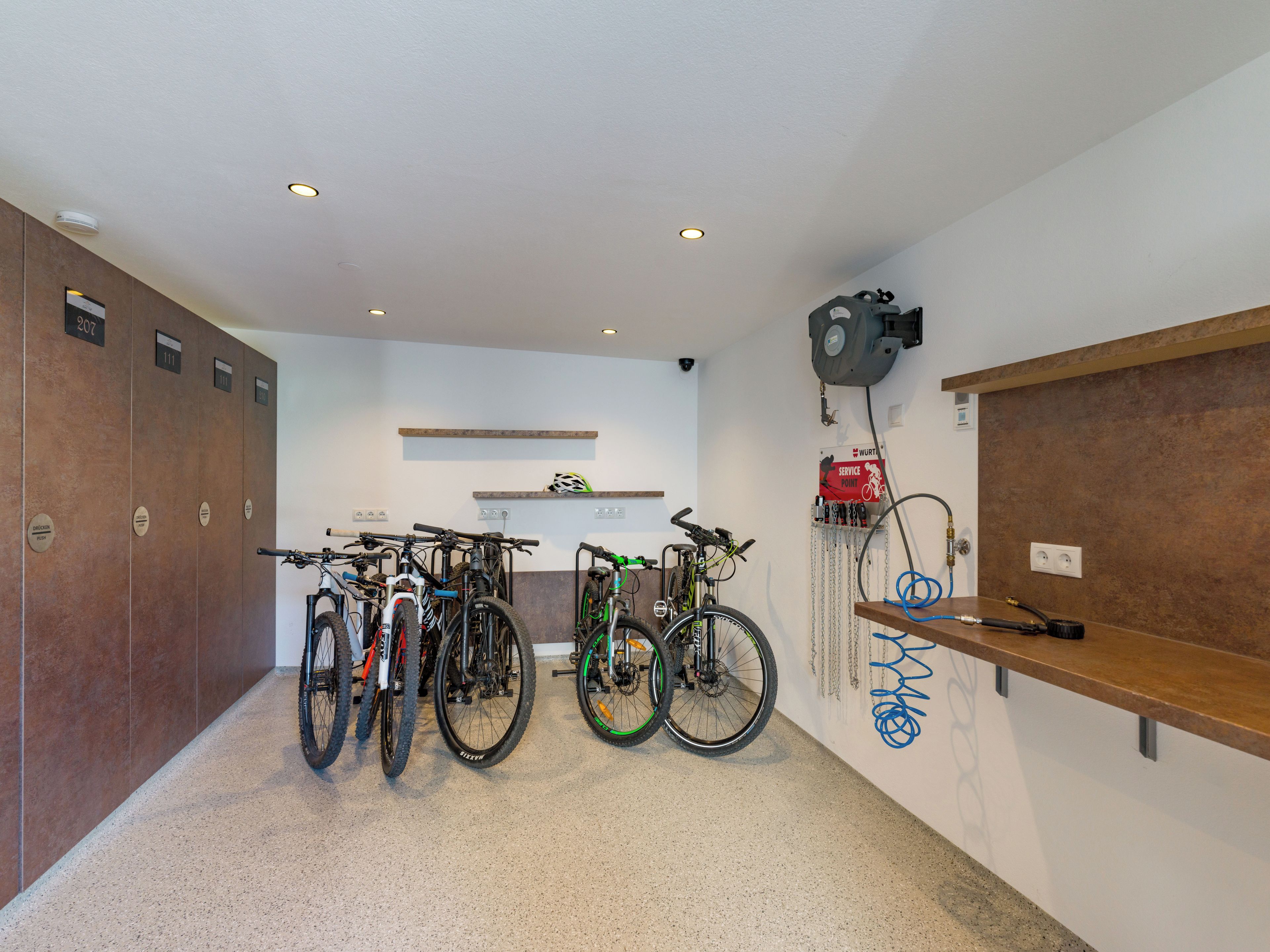 A bike storage area with multiple bicycles, a service point sign, and a water station.