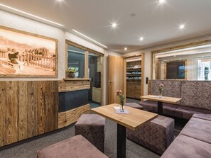A modern interior with wooden paneling, a seating area with cushioned benches, and a reception desk. - Garni Nill (Schwendau)