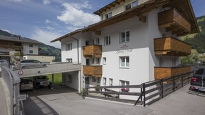 A multi-story building with balconies, a garage, and a sign indicating a parking area. - Garni Nill (Schwendau)