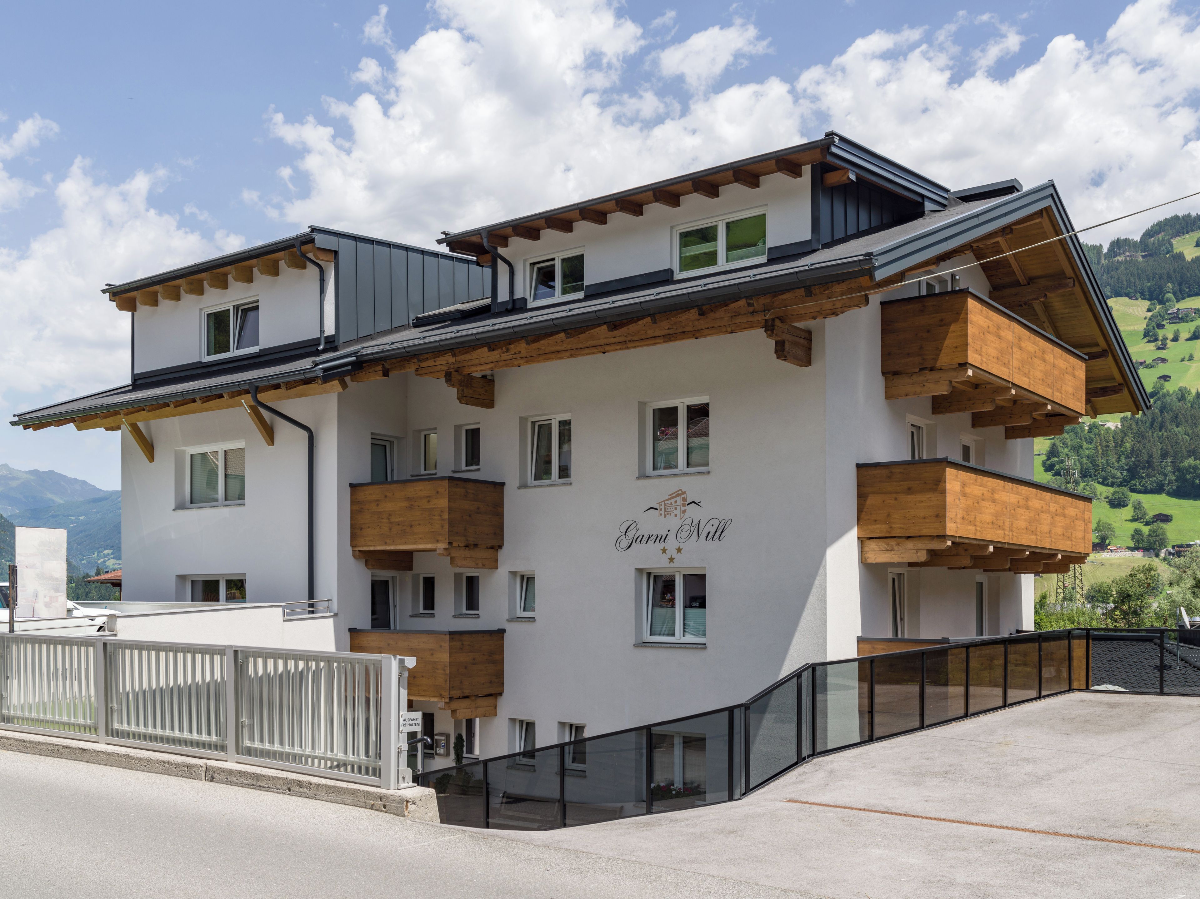 A multi-story building with balconies, a name sign, and a view of the surrounding landscape.