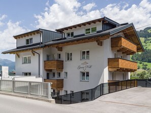 A multi-story building with balconies, a name sign, and a view of the surrounding landscape. - Garni Nill (Schwendau)