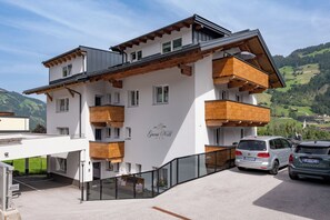 A multi-story building with wooden balconies, a sign reading 'Garni Will,' and a view of a green valley. - Garni Nill (Schwendau)