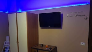 A room with a TV mounted on the wall, a wooden cabinet with a nameplate, and a motivational quote on the wall. - B&B Fragranza Di Sicilia (Giardini Naxos)