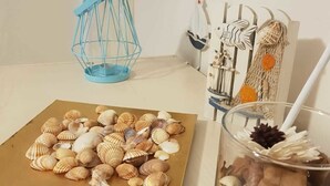 A table with a plate of seashells, a decorative lantern, and a glass container with dried flowers and seeds. - B&B Fragranza Di Sicilia (Giardini Naxos)