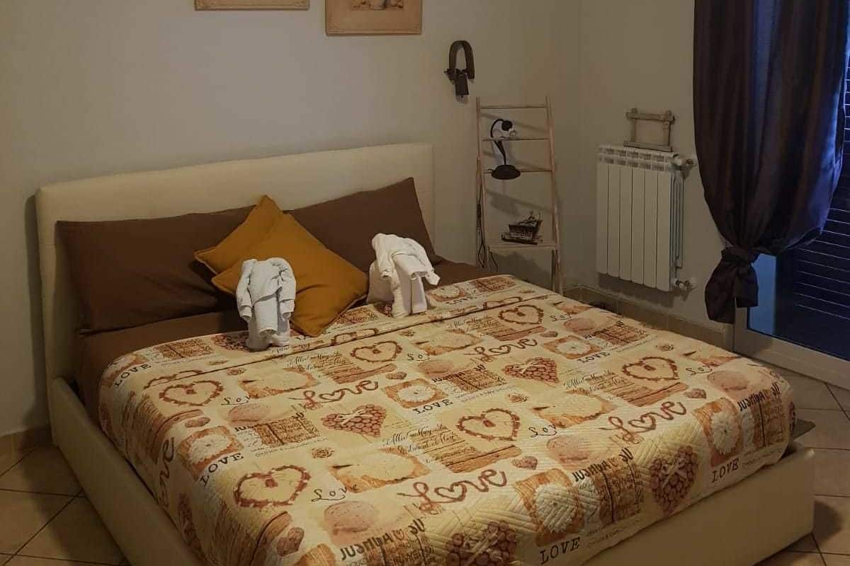 Une chambre à coucher avec un lit, un ventilateur de plafond, un radiateur et une fenêtre avec des rideaux.