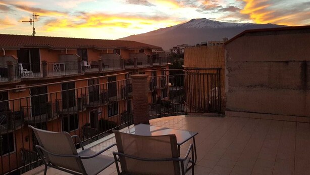 A terrace with two chairs and a table, overlooking a mountain and a sunset. - B&B Fragranza Di Sicilia (Giardini Naxos)