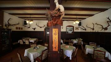 Ein Restaurant mit Holztischen, -stühlen und Geweih-Dekoration an den Wänden.