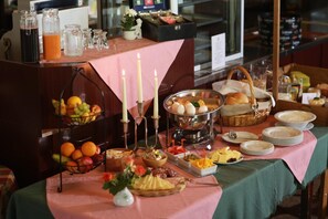 A buffet setup with various food items, including fruits, eggs, and bread, on a pink tablecloth. - Gaststätte & Pension Lichtenhainer Wasserfall (Sebnitz)