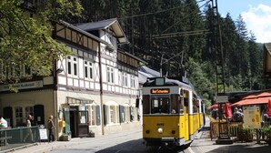A yellow and white tram with "Rad Schandau" on the front, passing by a building with a sign "Viehhandel Schandau". - Gaststätte & Pension Lichtenhainer Wasserfall (Sebnitz)