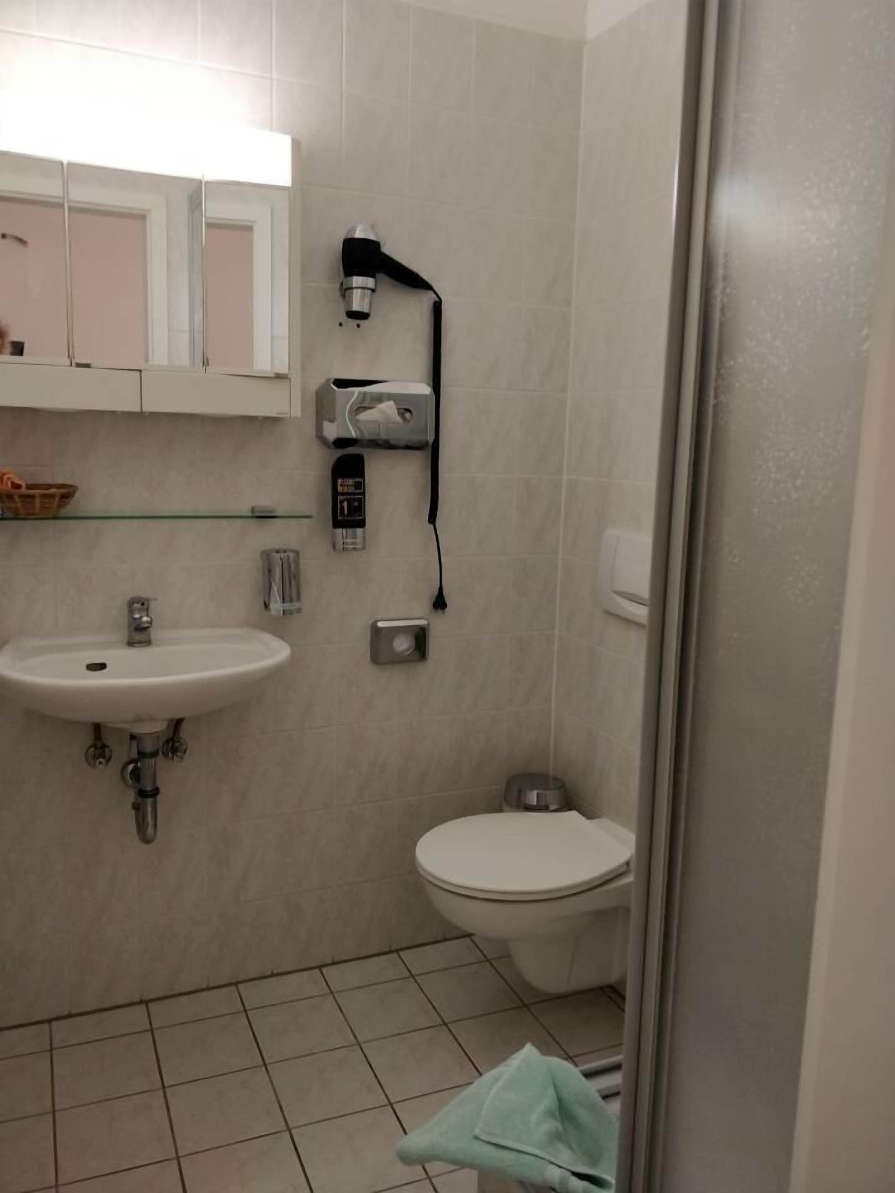 Casa de banho com lavatório, sanita e secador de mãos.