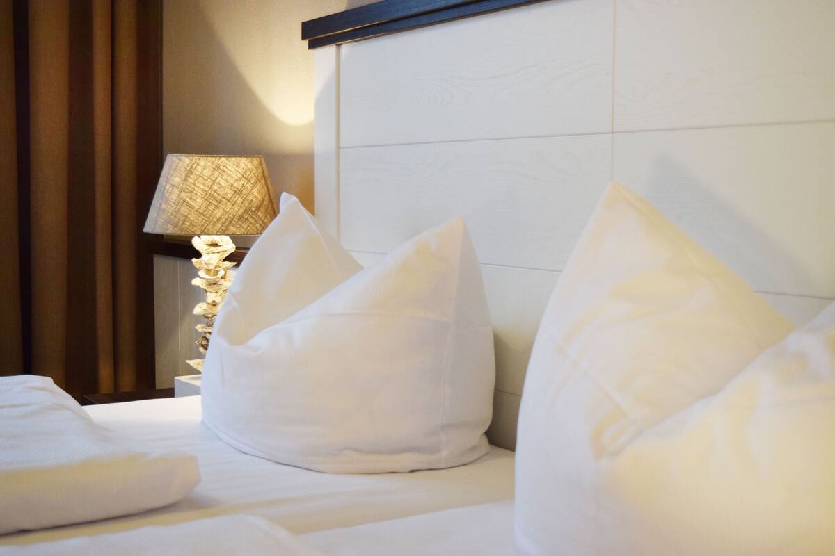 Una habitación de hotel con una cama bien hecha, una lámpara y un estante en la pared.