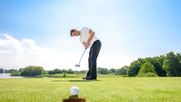 Eine Person auf einem Golfplatz, bereit, einen Ball zu schlagen.