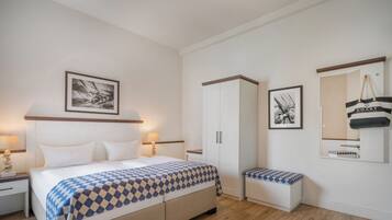 Ein Schlafzimmer mit einem Bett, Nachttischen, einer Bank, einem Kleiderschrank und gerahmten Bildern an der Wand.