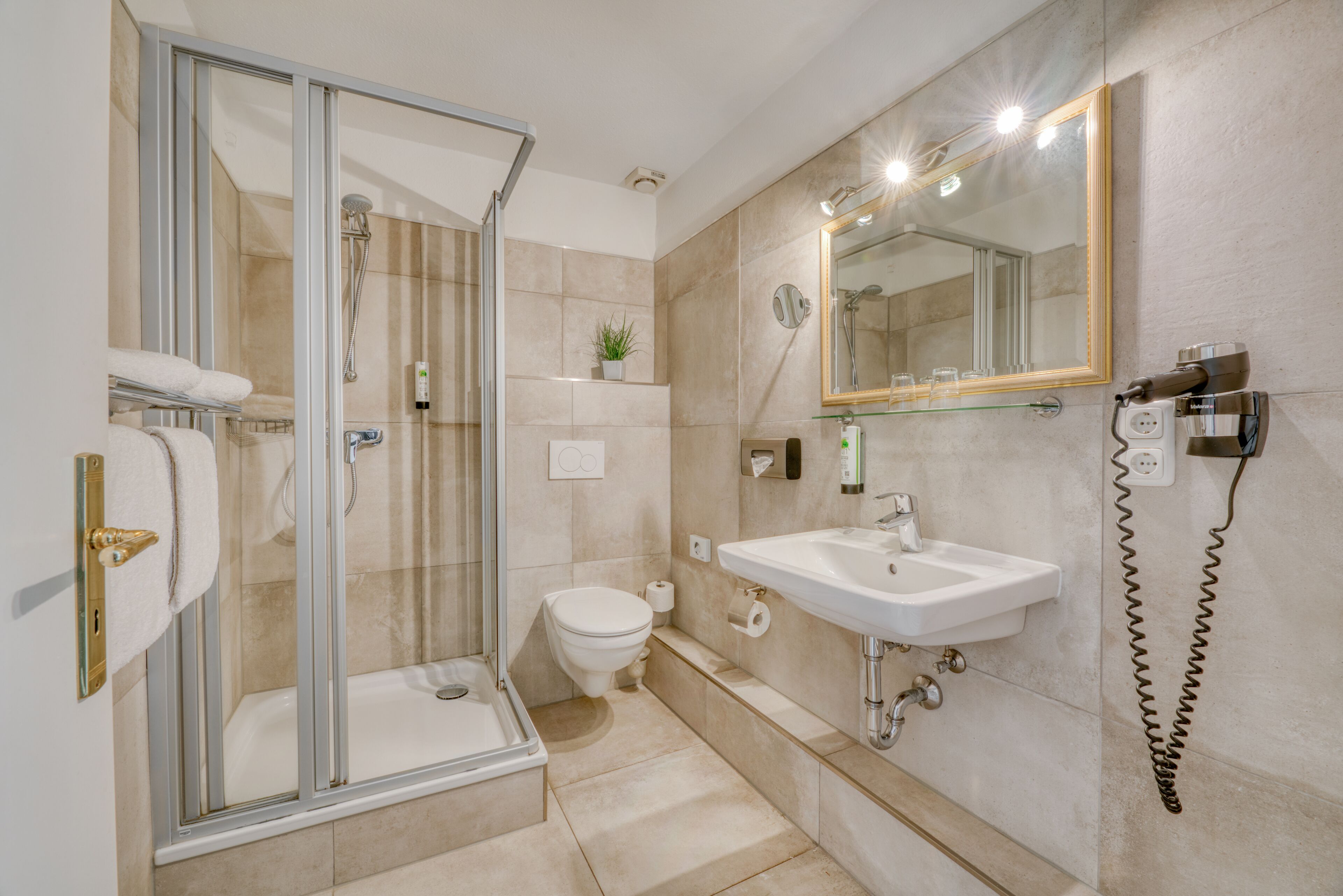 A modern bathroom with a glass-enclosed shower, a white sink, and a large mirror.