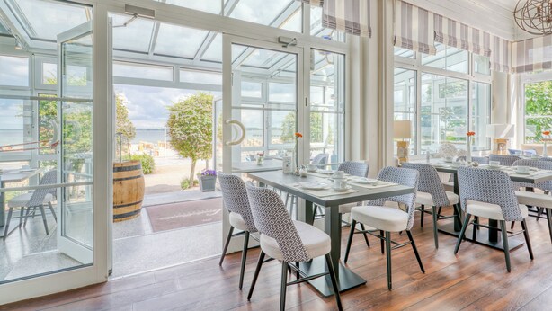 Un espace repas doté de portes vitrées donnant sur une terrasse extérieure, d ’un plancher en bois et de chaises à motifs.