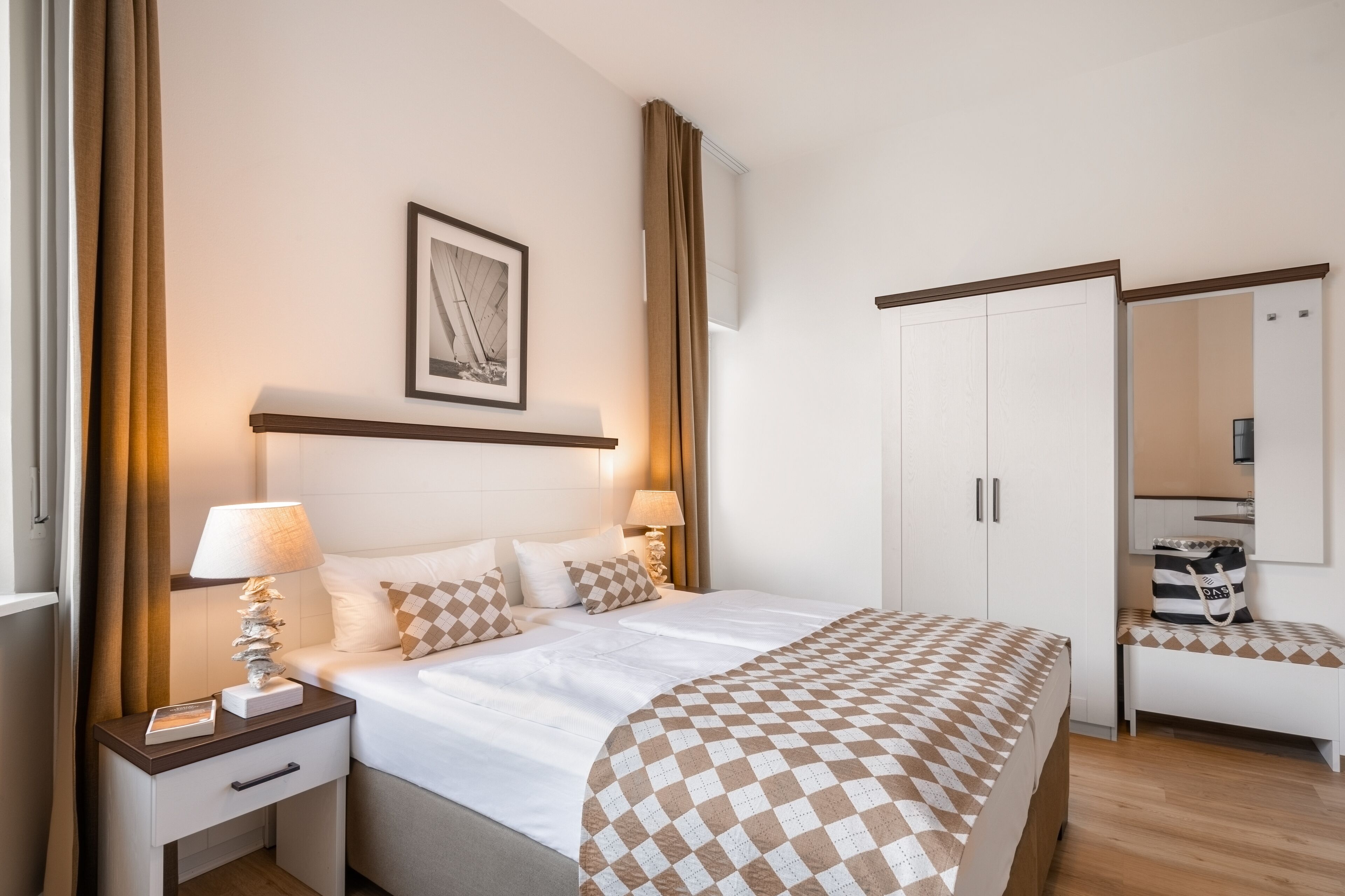 Camera d'albergo con un letto, comodini, un guardaroba, una panca e uno specchio.