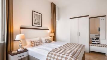 Camera d'albergo con un letto, comodini, un guardaroba, una panca e uno specchio.