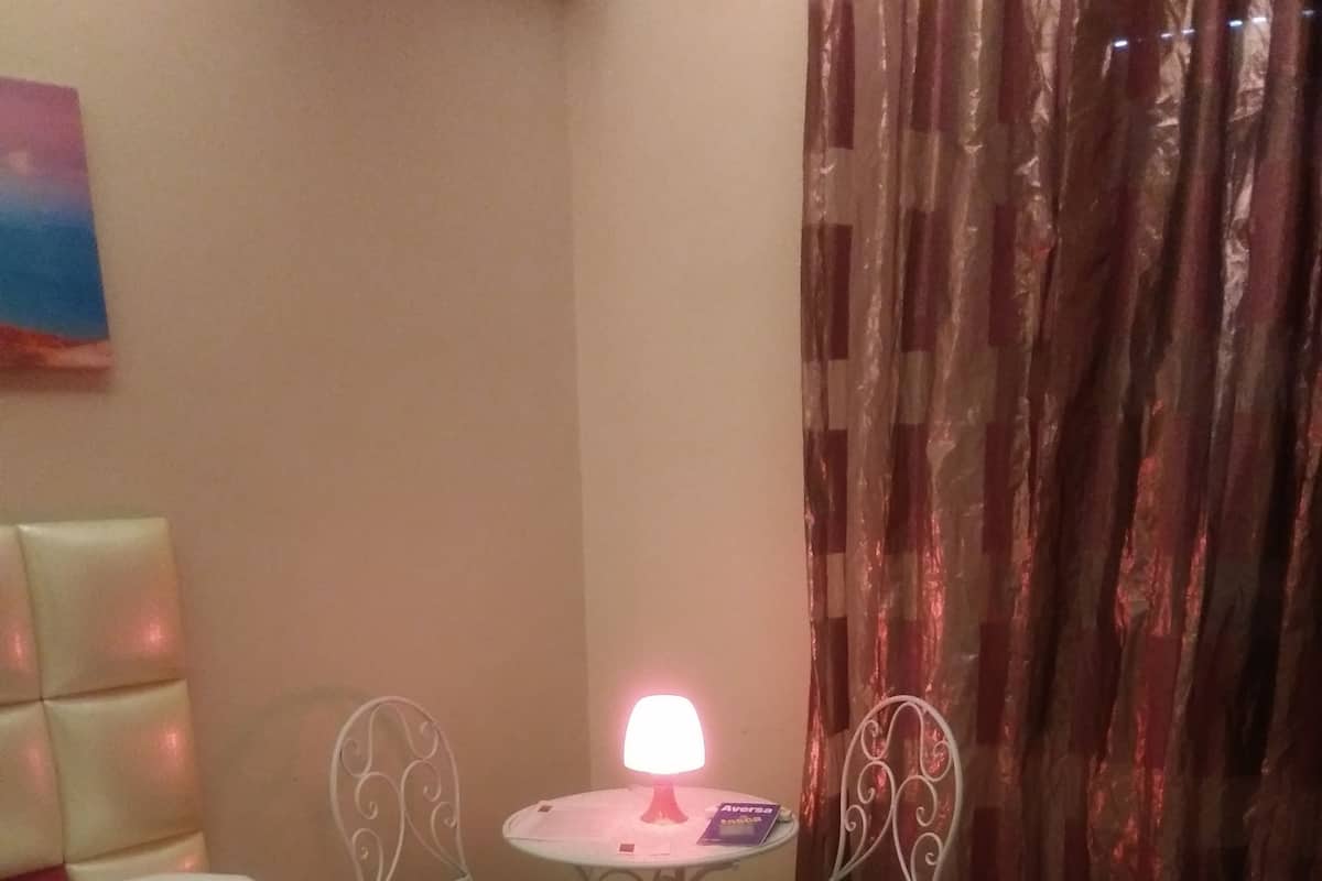 A bedroom with a bed, a table with chairs, and a lamp.