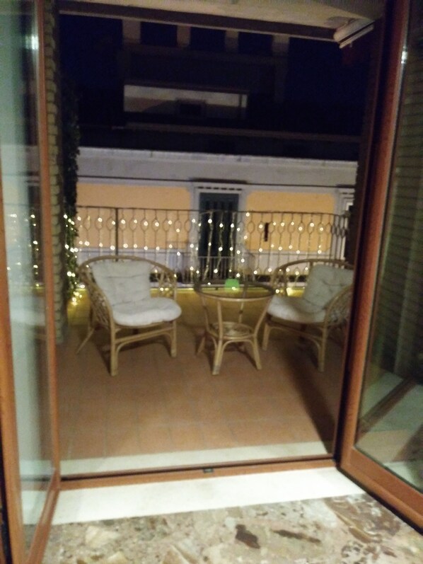 A balcony with wicker chairs and a table, decorated with string lights. - A Casa Carmen (Aversa)