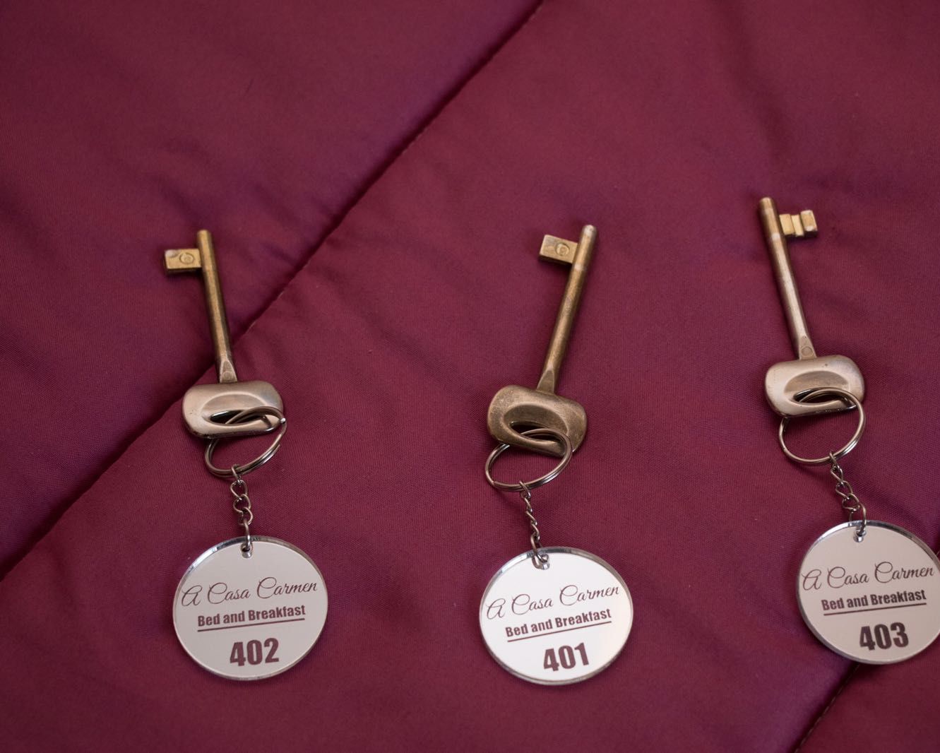 Tre portachiavi con i numeri 402, 401 e 403, ognuno riporta la scritta 'A Casa Carmen Bed and Breakfast'.
