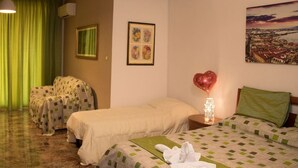 A hotel room with two beds, a green curtain, a framed floral artwork, a heart-shaped balloon, and a cityscape painting. - A Casa Carmen (Aversa)