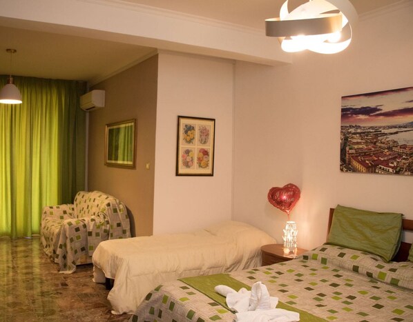 A hotel room with two beds, a green curtain, a framed floral artwork, a heart-shaped balloon, and a cityscape painting. - A Casa Carmen (Aversa)