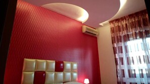 A hotel room with a red wall, a headboard with a light-colored cushion, and a window with sheer curtains. - A Casa Carmen (Aversa)