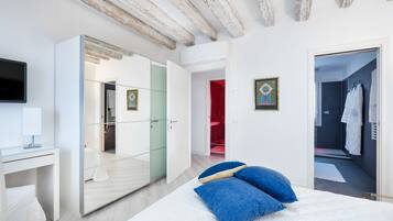 Un dormitorio moderno con cama, escritorio, televisor y vestidor.